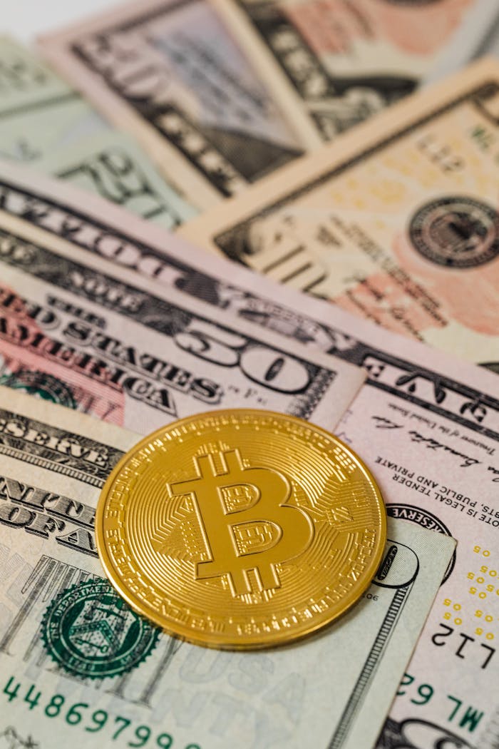 Close-up of a golden Bitcoin coin on various US dollar bills, symbolizing cryptocurrency and finance.