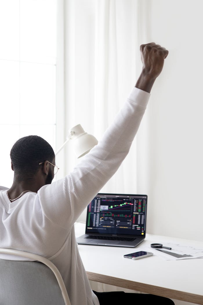 brand-03 A man celebrates a successful stock market trade while sitting at his desk.